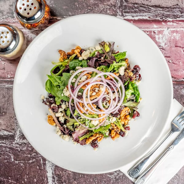 Marri's Pizza & Pasta's mixed green salad with walnuts, cranberries, blue cheese, and red onion.
