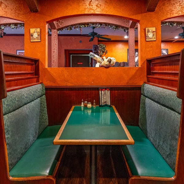 Cozy booth seating with green upholstery and a wooden table at Marri's Pizza & Pasta.